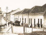 Rua Manoel Ribas na �poca em que a Via��o F�rrea ainda estava em funcionamento.   � esquerda, em primeiro plano, a pharmacia, seguida pelos armaz�ns e pelo escrit�rio da empresa