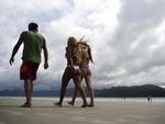 Algumas pessoas aproveitam para caminhar na praia que est quase deserta 