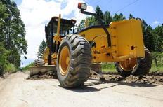 Máquina da Prefeitura passa para nivelar a estrada, que fica cheia de buracos depois da chuva - Claudia Baartsch / Agencia RBS