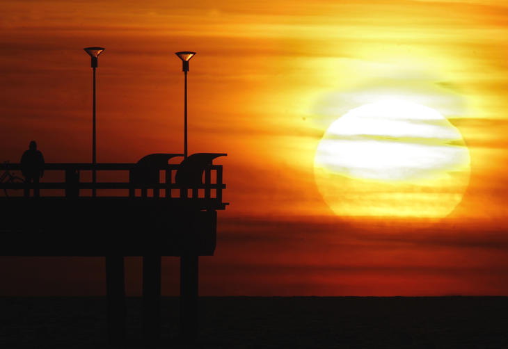 Um homem assiste pr-do-sol no cais em Palanga, na Lituania.