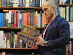 Na Livraria e Papelaria Blu Livro - Ninja veste T-shirt Von der Volke,cala jeans Armani, blazer Calvin Klein, cinto Sergio K e bota Osklen
