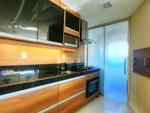 Na cozinha aberta para o living, os armrios sob medida tem acabamento melamnico amadeirado e vidro preto