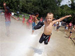 Enaquanto a chuva na vem, Shawn Aiken Jr., 5 anos, se diverte com jatos da gua em um parque de Boston, EUA
