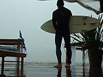 Domingo: O dia alternou momentos de sol e chuva. Surfista em Atlntida observa a praia com tempo fechado