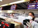 Cuba - Uma funcionria do aeroporto internacional Jos Mart, de onde saem voos para o Mxico, se cobre uma mscara em La Havana. As autoridades sanitrias esto adotando todas as medidas necessrias