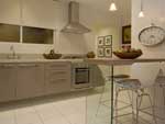 Assim como na rea social, o arquiteto Raul Pgas elegeu os tons branco e fendi para a cozinha, de 10,67 metros quadrados, em um dos modelos de apartamentos da Rossi Residencial. Enquanto o primeiro tom imprime cor ao piso de porcelaneto, forro de gesso e paredes, o segundo colore a marcenaria. Com tampo revestido por lmina que imita madeira clara e p de acrlico translcido, a mesa ganha a companhia das banquetas altas na ambientao da copa - espao para lanches e refeies rpidas