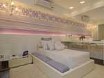 Para a sute da menina, de 12,39 metros quadrados, a arquiteta paulista elegeu a cor lils, aplicada em diferentes tons no adesivo decorativo da parede da cama e nas almofadas e futons. Painel de MDF com laca branca colocado em meia-parede forma a cabeceira, em composio de material com o tablado da cama e com a bancada de estudo e maquiagem. Mesa baixa espelhada e cadeira Ghost de acrlico transparente, do designer Philippe Starck, conferem visual moderno ao espao