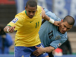 Robinho tenta passar pela forte marcao do uruguaio Maximiliano Pereira
