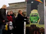 Em Berlim, a secretria de Estado dos Estados Unidos, Hillary Clinton observa uma das peas da cedeia de gigantescas peas de domin que simbolizar a queda do Muro de Berlim
