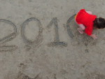 Criana brinca com o &quot;2010&quot; gravado na areia, no Litoral  Norte