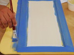 Passo 6: passe sobre a pintura amarela uma demo da tinta azul claro. Pinte tambm de azul claro os ganchos de madeira. Deixe secar.
