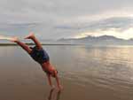 Menino faz piruetas na beira da praia