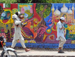 Paquistaneses passam por uma parede pintada com grafite ao longo de uma rua na cidade de Lahore
