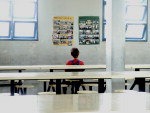 Aluno que ficou sem aula olha trabalhos expostos no refeitrio vazio